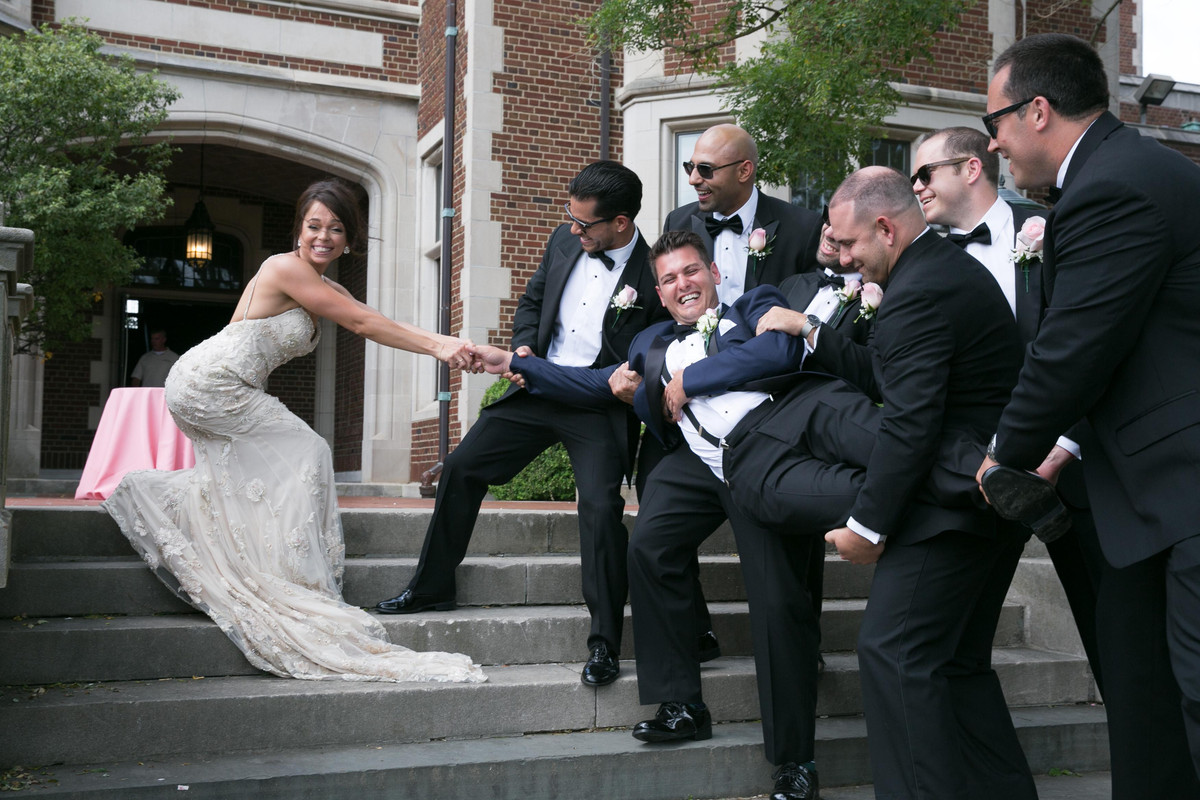 A wedding party laughing together on stone steps